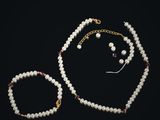 un ensemble composé d'un collier et d'un bracelet en perles blanches, avec un fermoir plaqué or