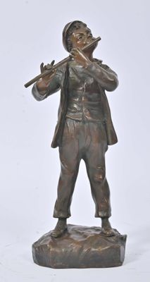bronze statue of a man playing a flute on a rock