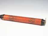 an old red cylinder with writing on it sitting on a white surface