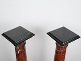 a pair of red marble pedestals with black bases