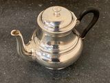 a silver tea pot sitting on the ground on the ground