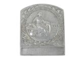 a silver plaque with a woman sitting on a bench