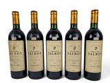 four bottles of red wine are lined up on a white surface