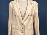 cream colored jacket on a mannequin stand with a blue background