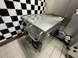 a stainless steel table in a kitchen with a checkered wall behind it