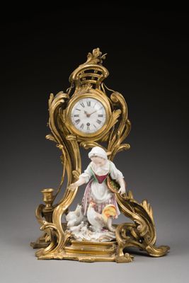 une horloge en or ornée d'une figurine représentant une femme tenant un panier