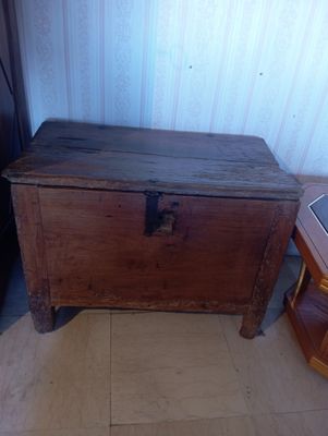 un coffre en bois posé par terre à côté d'une petite table