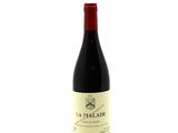 a bottle of red wine sitting on top of a white table