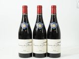 trois bouteilles de vin rouge posées l'une à côté de l'autre sur une surface blanche