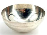a silver bowl that is sitting on a white surface