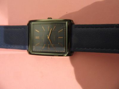 une montre noire et dorée montée sur un bracelet en cuir noir