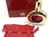 an image of a bottle of perfume next to a red bag
