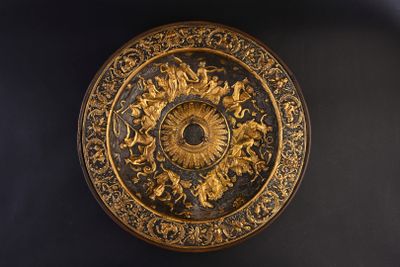 a gold plate with a clock on it on a black wall