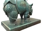 bronze sculpture of a rhinocero on a marble base on a white background