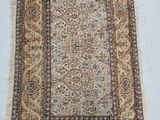 un tapis posé sur un sol blanc, bordé d'une frange marron