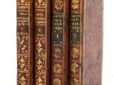 trois vieux livres sont empilés sur une surface blanche