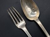two silver spoons and a fork on a black surface