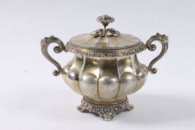 une théière ancienne en métal argenté, avec couvercle, posée sur un socle