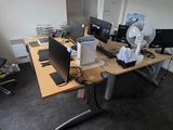 a desk with two computers and a fan in the corner