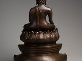 a bronze statue of a buddha sitting on a lotus flower