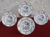 four plates with floral designs on them sitting on a red surface