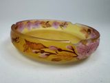 a yellow bowl with pink flowers on it on a table