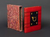 un livre rouge orné d'une lettre dorée et un livre rouge orné d'une lettre dorée