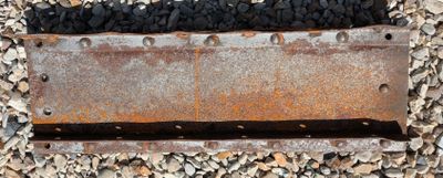 a rusted piece of metal on the ground next to rocks