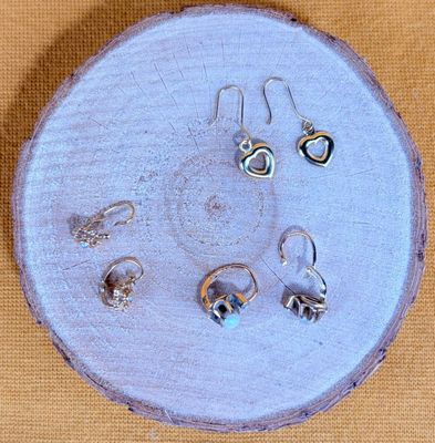 cinq paires de boucles d'oreilles posées sur un morceau de bois