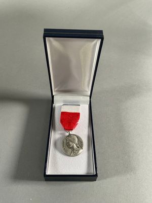 a silver medal with a red ribbon in a black box