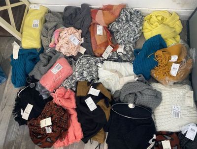 a box full of sweaters and scarves on the floor