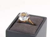 une bague en diamant dans un écrin noir posé sur une surface blanche