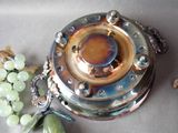 a silver plate with a green bead on it next to a bunch of grapes