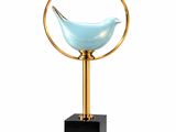 a blue glass bird sitting on top of a gold stand
