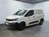 La camionnette blanche est garée dans une grande pièce aux murs blancs.