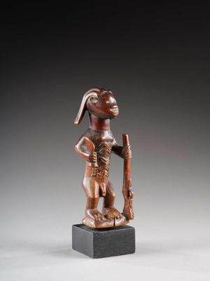 une statue en bronze représentant un homme coiffé d'un chapeau et muni d'une canne