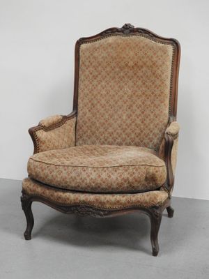 une chaise à l'ancienne dont le dossier est recouvert d'un tissu à motifs floraux