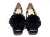 pair of women ' s black shoes with black fur pom poms on them