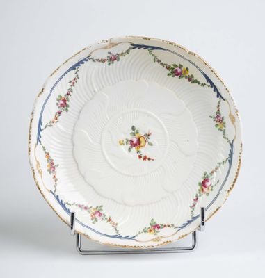 une assiette blanche décorée de fleurs, posée sur un support