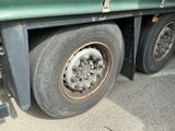un camion vert avec un pneu crevé, garé sur le bord de la route
