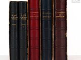 trois vieux livres sont alignés sur une surface blanche