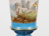 un vase bleu avec une peinture dessus, posé sur une table
