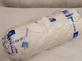 un rouleau de papier toilette emballé dans du plastique, posé sur un lit