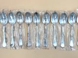 six cuillères en argent dans un sac en plastique posé sur une table
