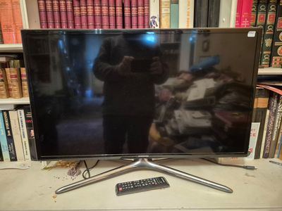 a flat screen tv sitting on a table in front of a bookshelf