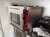 a silver oven with a red handle in a kitchen