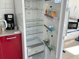 an open refrigerator in a kitchen with a red cabinet