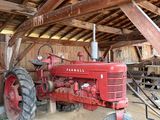 un tracteur rouge garé à l'intérieur d'une grange au toit en bois