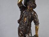bronze statue of a boy holding a basket and a baseball bat
