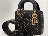 un sac à main noir avec des anses cloutées d'or et une ceinture